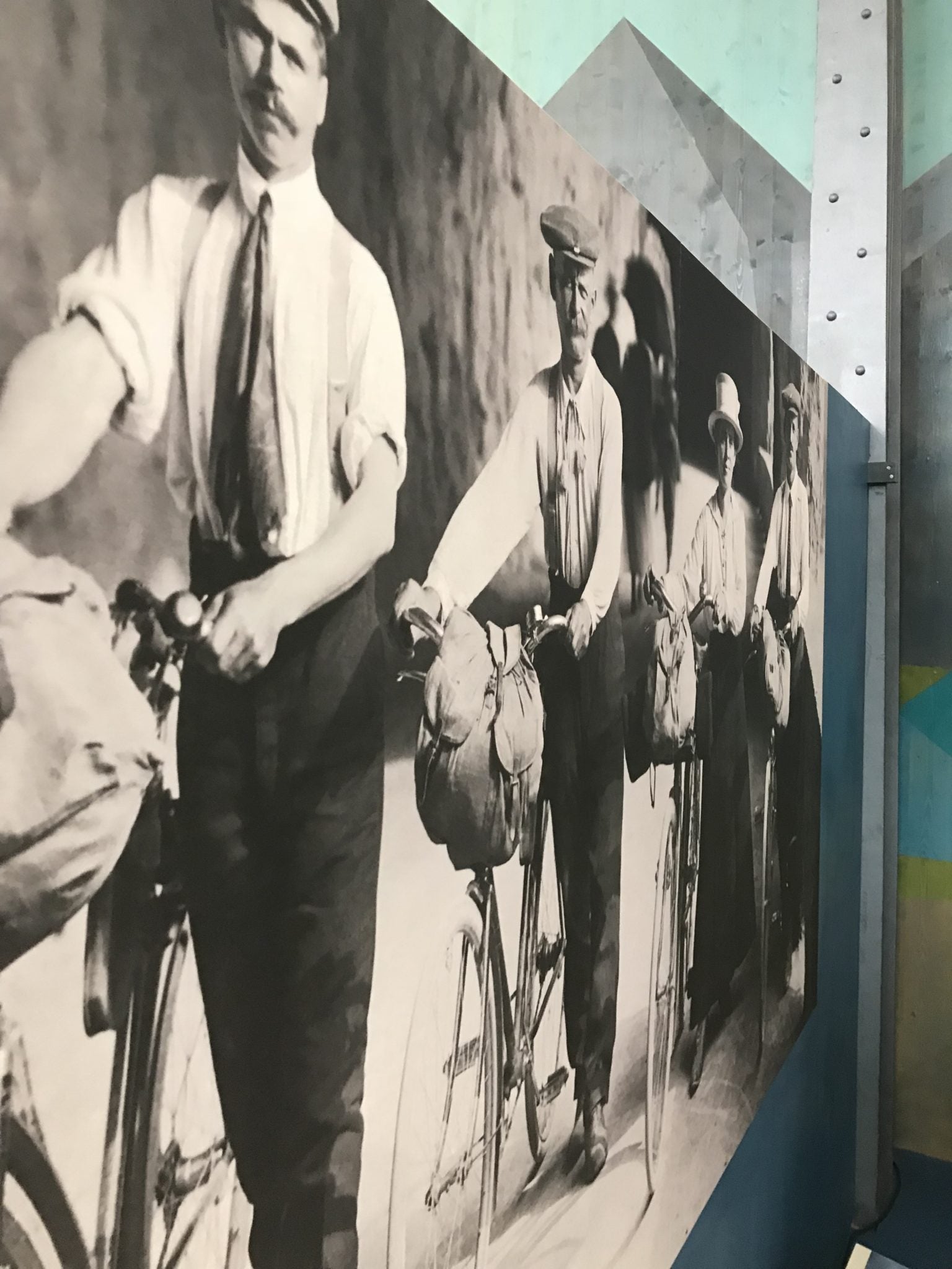 Urzekające zdjęcie mężczyzn na rowerach, ukazujące bogatą historię i ewolucję 200 lat roweru w muzeum.