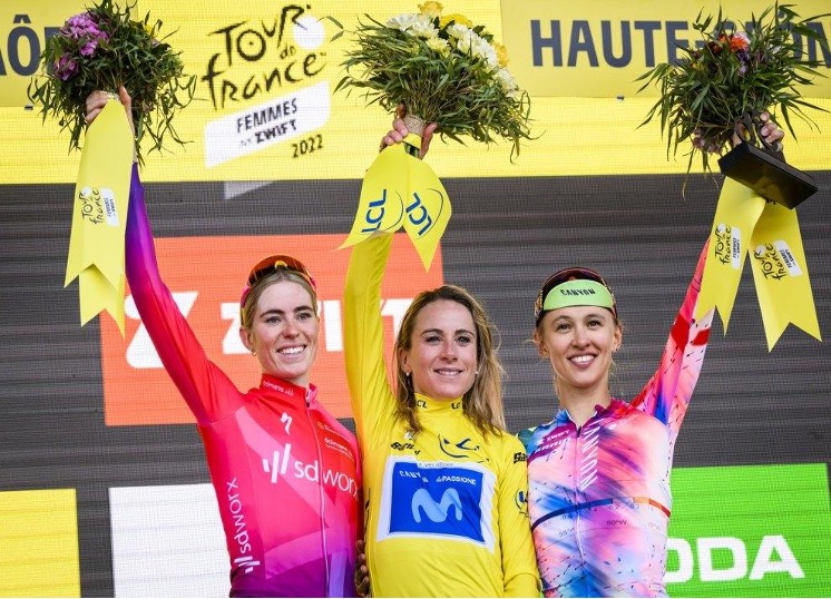 Trzy cyklistki stojące na podium z kwiatami.