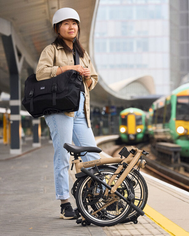 Kobieta stojąca na peronie z rowerem Brompton - czarna na stacji kolejowej.