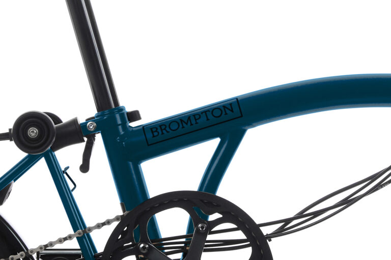 Zbliżenie na turkusową ramę roweru składanego Brompton C-line M6R Ocean Blue, przedstawiającą część łańcucha, koło i sztycę.