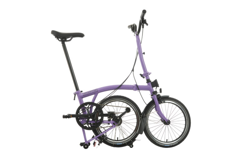 Fioletowy rower składany z czarnymi kołami i komponentami, odizolowany na białym tle.