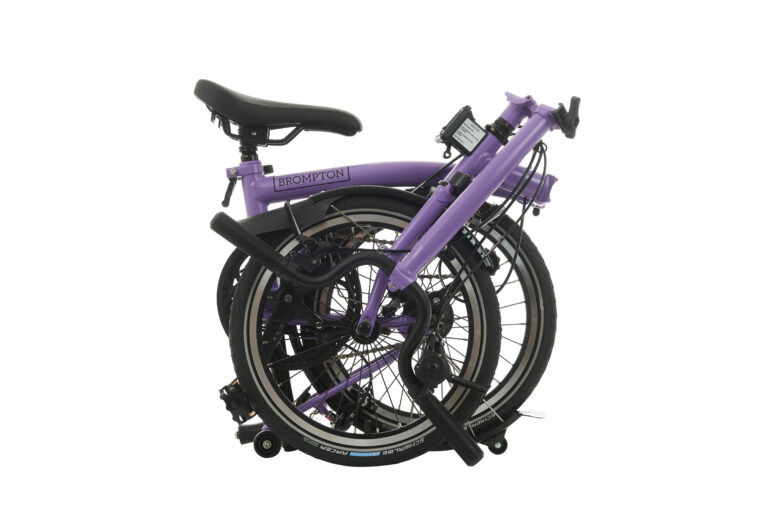 Złożony fioletowy rower Brompton na białym tle.