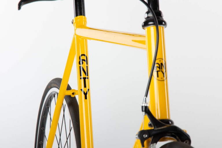 An Antymateria Miasto ON - żółty rower 59 cm z czarną kierownicą.