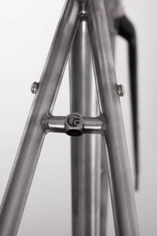 Zbliżenie złącza rury podsiodłowej ramy roweru ze złączami spawanymi i występami montażowymi.
