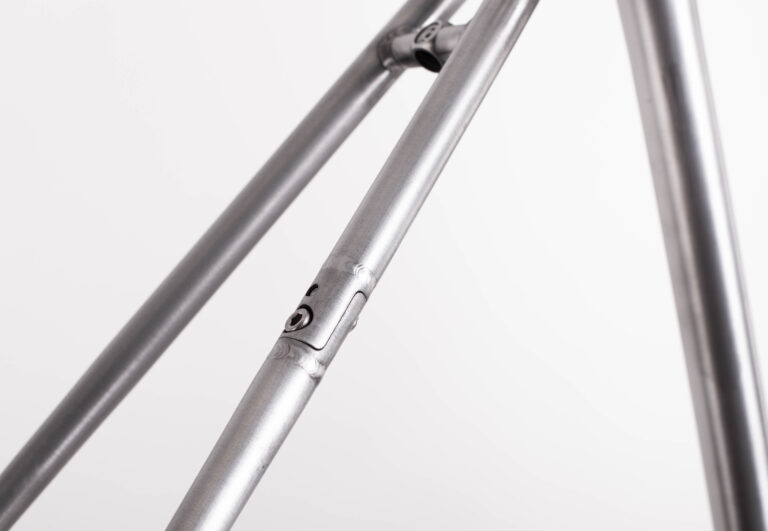 Zbliżenie metalowej ramy roweru przedstawiające szew spawalniczy i szczegóły połączeń.