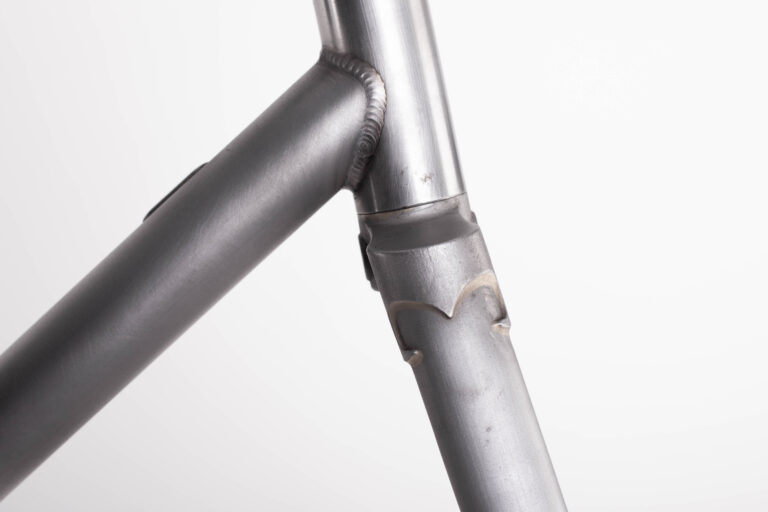 Zbliżenie połączeń spawanych na metalowej ramie roweru.