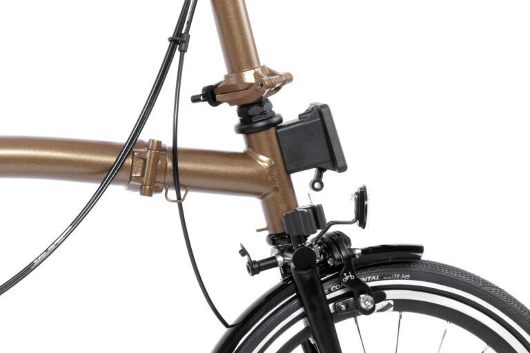 Zbliżenie przedniej części Brompton P-line Urban M4R Bronze Sky, przedstawiające kierownicę, linki hamulca, mechanizm zawiasów i część przedniego koła przymocowaną do ramy.