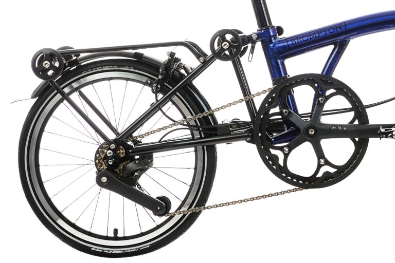 Zbliżenie na tylne koło i układ napędowy niebieskiego roweru składanego Brompton.