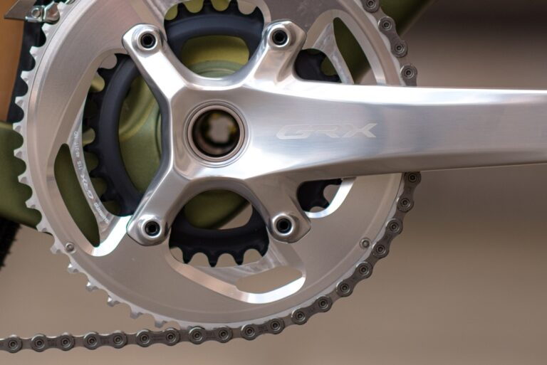 Zbliżenie na rowerowy mechanizm korbowy i tarcze z logo „grx”, podkreślające szczegółową inżynierię i projekt.