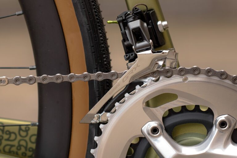 Zbliżenie na przerzutkę rowerową, przedstawiające szczegółowo łańcuch, przerzutkę i zębatki.