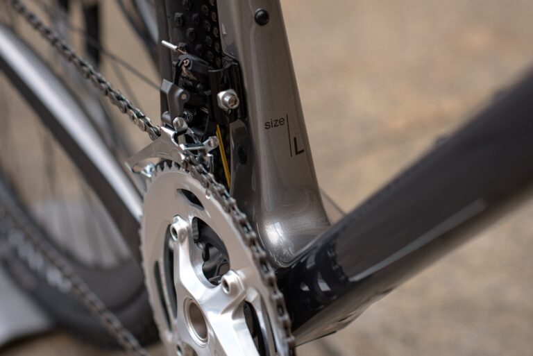 Zbliżenie na przerzutkę i łańcuch roweru na ramie w rozmiarze L, ze szczególnym uwzględnieniem mechaniki i błyszczących metalowych części.