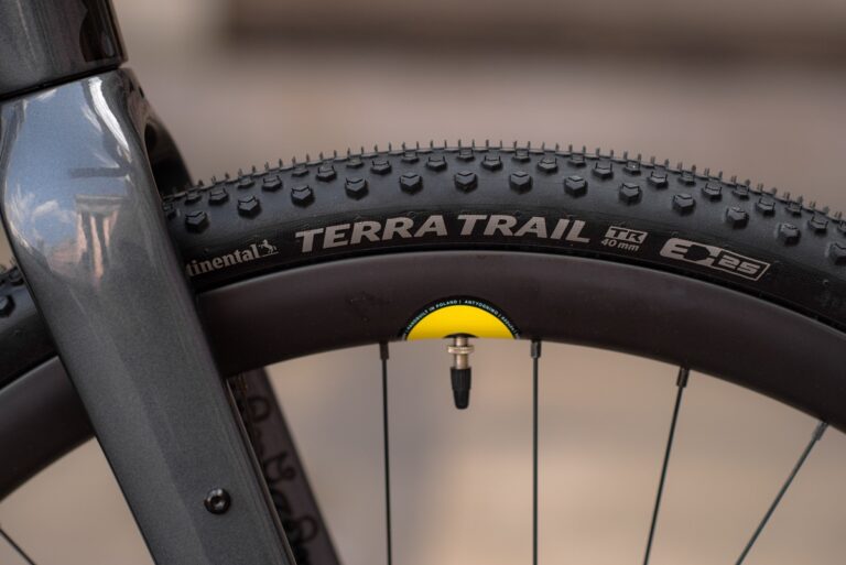 Zbliżenie na koło rowerowe z oponą Continental Terra Trail, podkreślające wzór bieżnika i żółte logo marki.