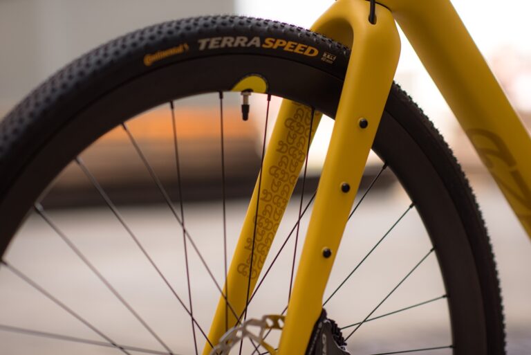 Zbliżenie na żółty widelec rowerowy Anty Gravel CRE M (54 cm) i czarną oponę z wyraźną etykietą „terraspeed”, na delikatnie rozmytym tle.
