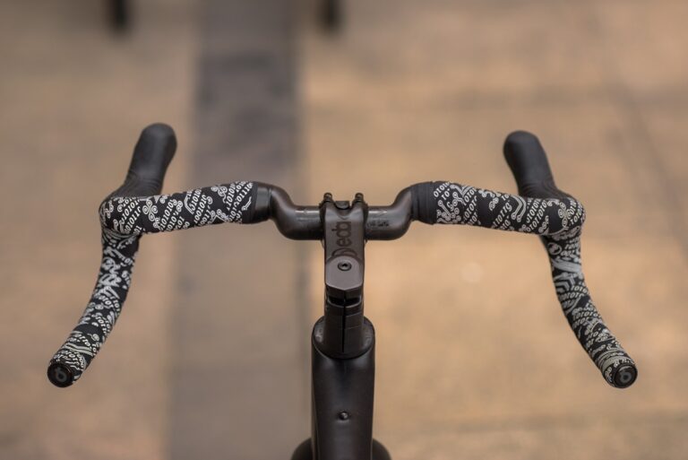 Zbliżenie na kierownicę roweru z taśmą antypoślizgową w misterny czarno-biały wzór.
