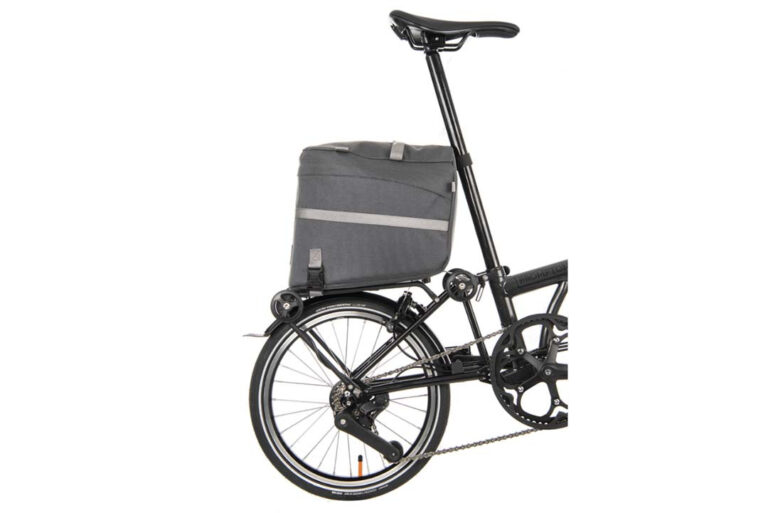 Czarny rower z przyczepioną do niego torbą na kółkach Torba Brompton Borough Roller Bag - ciemnoszara.