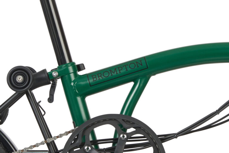 Zbliżenie na zielony rower składany Brompton C-line Explore Yuzu Lime, przedstawiające ramę i część mechanizmu łańcuchowego.